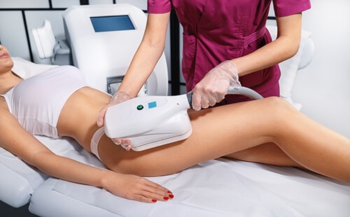 Young woman getting cryolipolyse treatment in cosmetic cabinet.