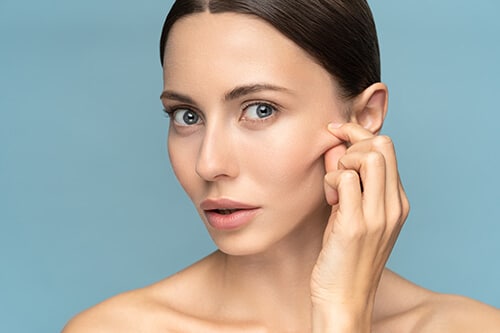 Woman without makeup touching cheeks after glycolic acid peel, h